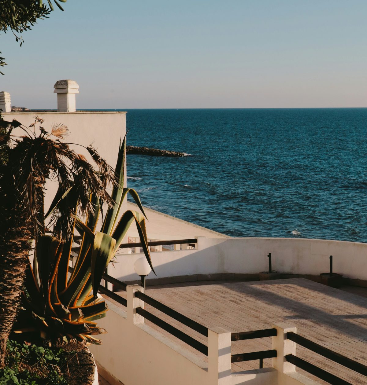 A sunlit seaside terrace above deep blue water
